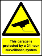 This garage is protected by a 24 hour surveillance system sign